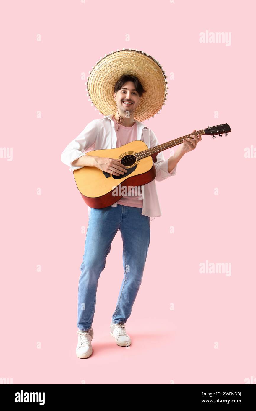 Jeune Mexicain en sombrero jouant de la guitare sur fond rose Banque D'Images
