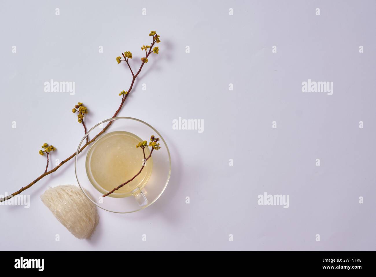 Une tasse transparente en verre contenant de la soupe de nid d’oiseau, décorée d’un nid d’oiseau comestible et de branches de fleurs. Le nid d’oiseau peut améliorer la prévention des maladies Banque D'Images