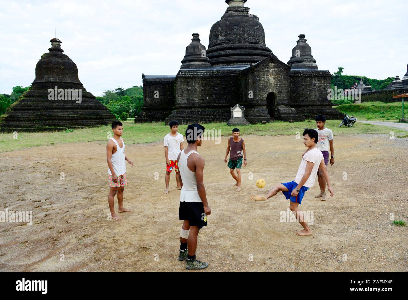 Hommes Arakanais jouant au football près de l'un des anciens templs à Mrauk-U, État de Rakhine, Myanmar. Banque D'Images