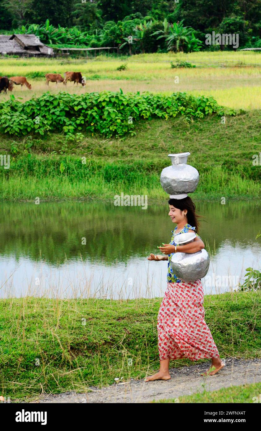 Une femme arakanaise transportant des cruches d'eau dans leur village de Mrauk-U dans l'État de Rakhine, Myanmar. Banque D'Images