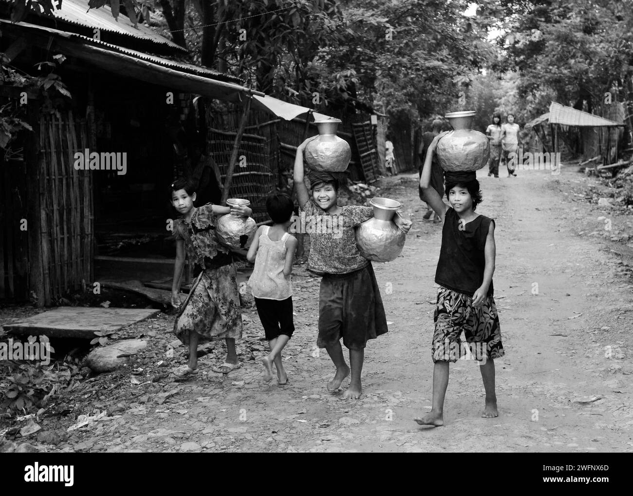 De jeunes filles arakanaises transportant des cruches à eau dans leur village de Mrauk-U dans l’État de Rakhine, au Myanmar. Banque D'Images