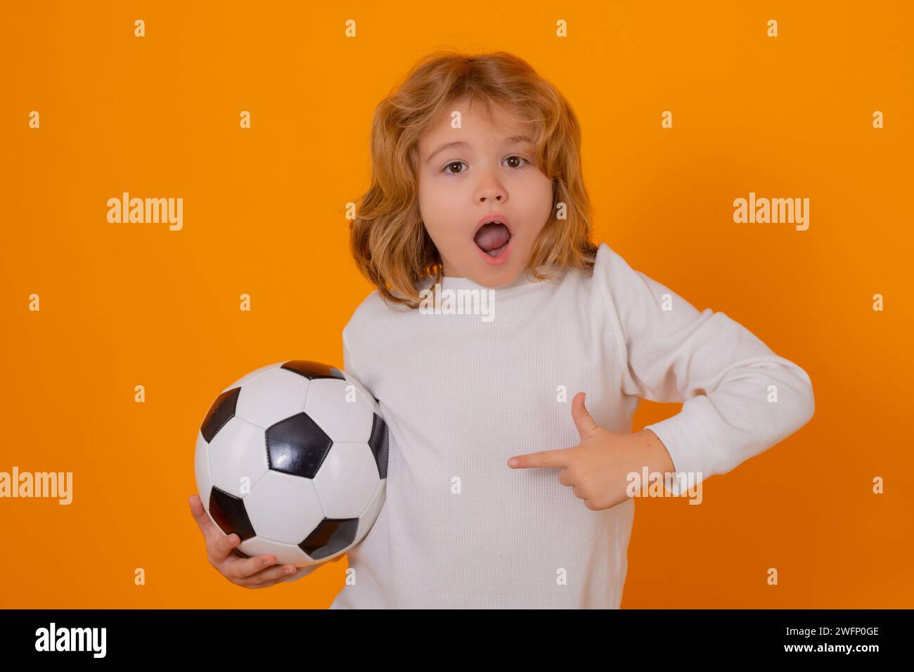 Enfant garçon tenir le ballon de football classique isolé sur le studio jaune. Enfant tenant un ballon de football en studio. Enfant jouant avec un ballon de football. Sport, football pour Banque D'Images