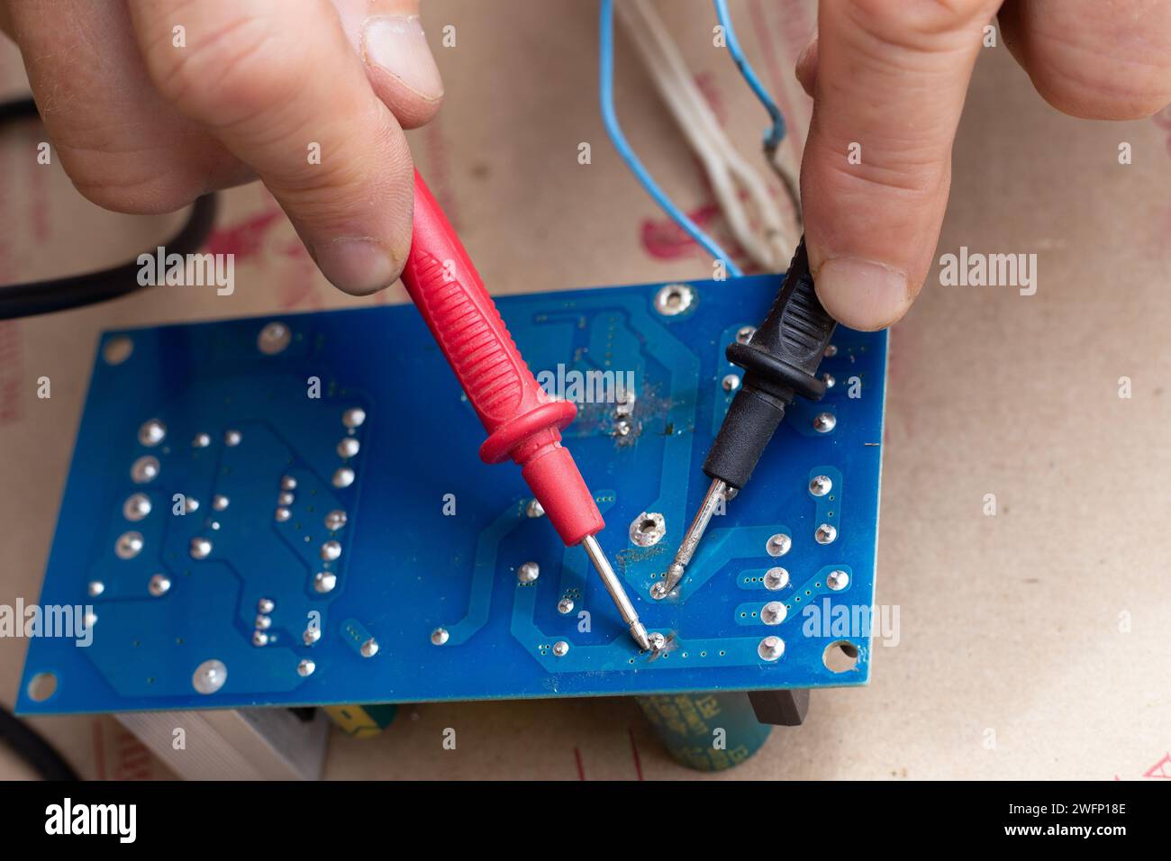 un travailleur vérifie les performances de l'alimentation électrique à l'aide d'un multimètre, gros plan. Condensateur d'alimentation. Banque D'Images