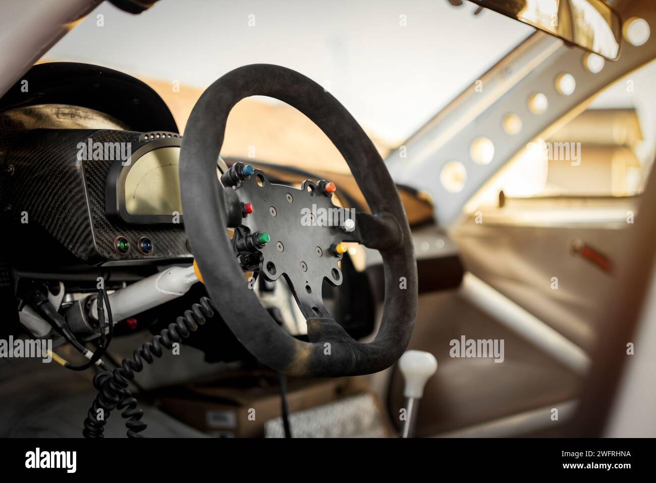 Intérieur de voiture de course, cockpit à la lumière chaude du coucher du soleil. Tableau de bord et volant revêtu de Suède. Banque D'Images