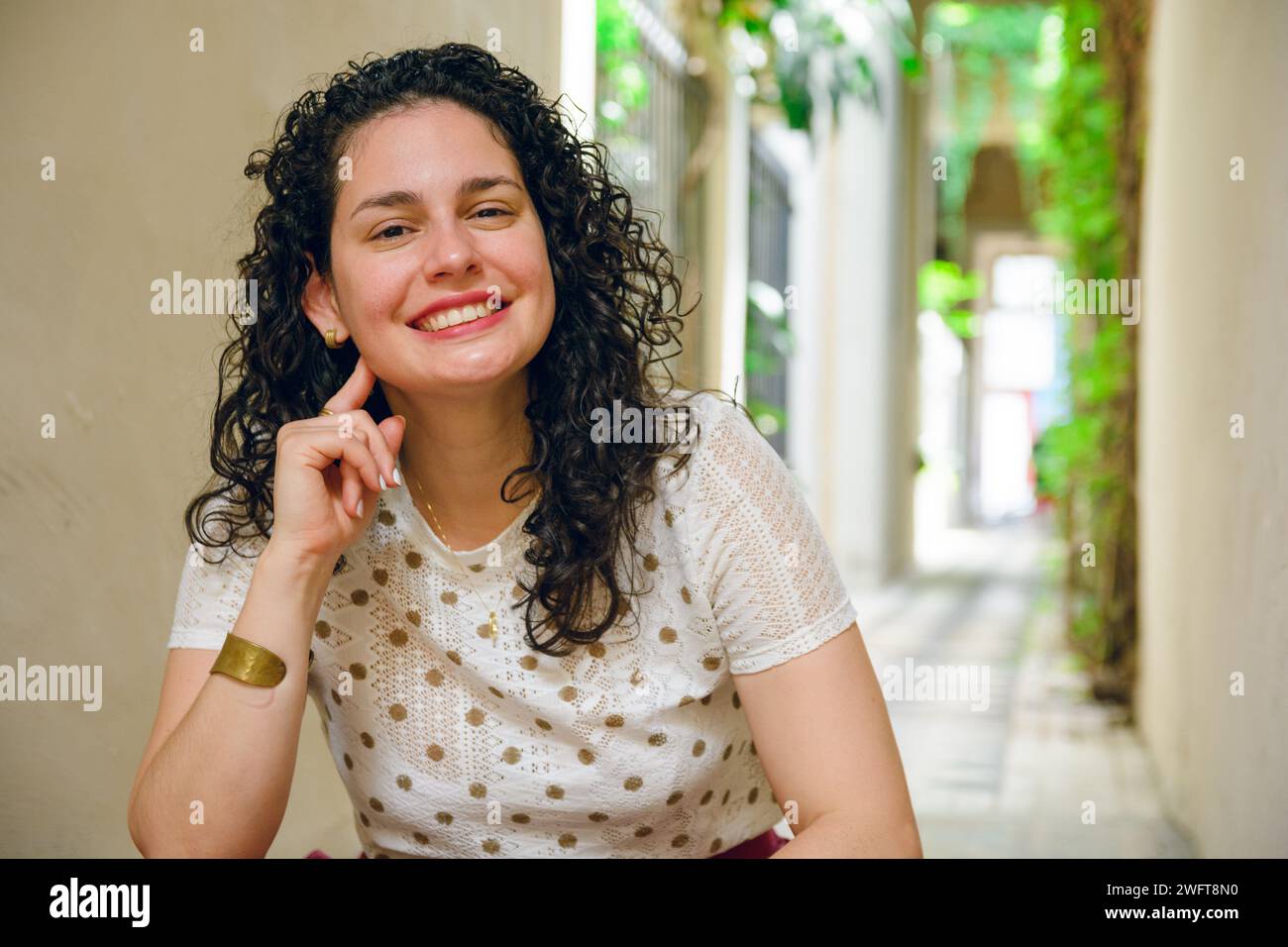 Heureuse jeune femme latine d'ethnie vénézuélienne avec des curleurs élégants, assis calmement souriant regardant la caméra, se sentant satisfaite, espace de copie. Banque D'Images