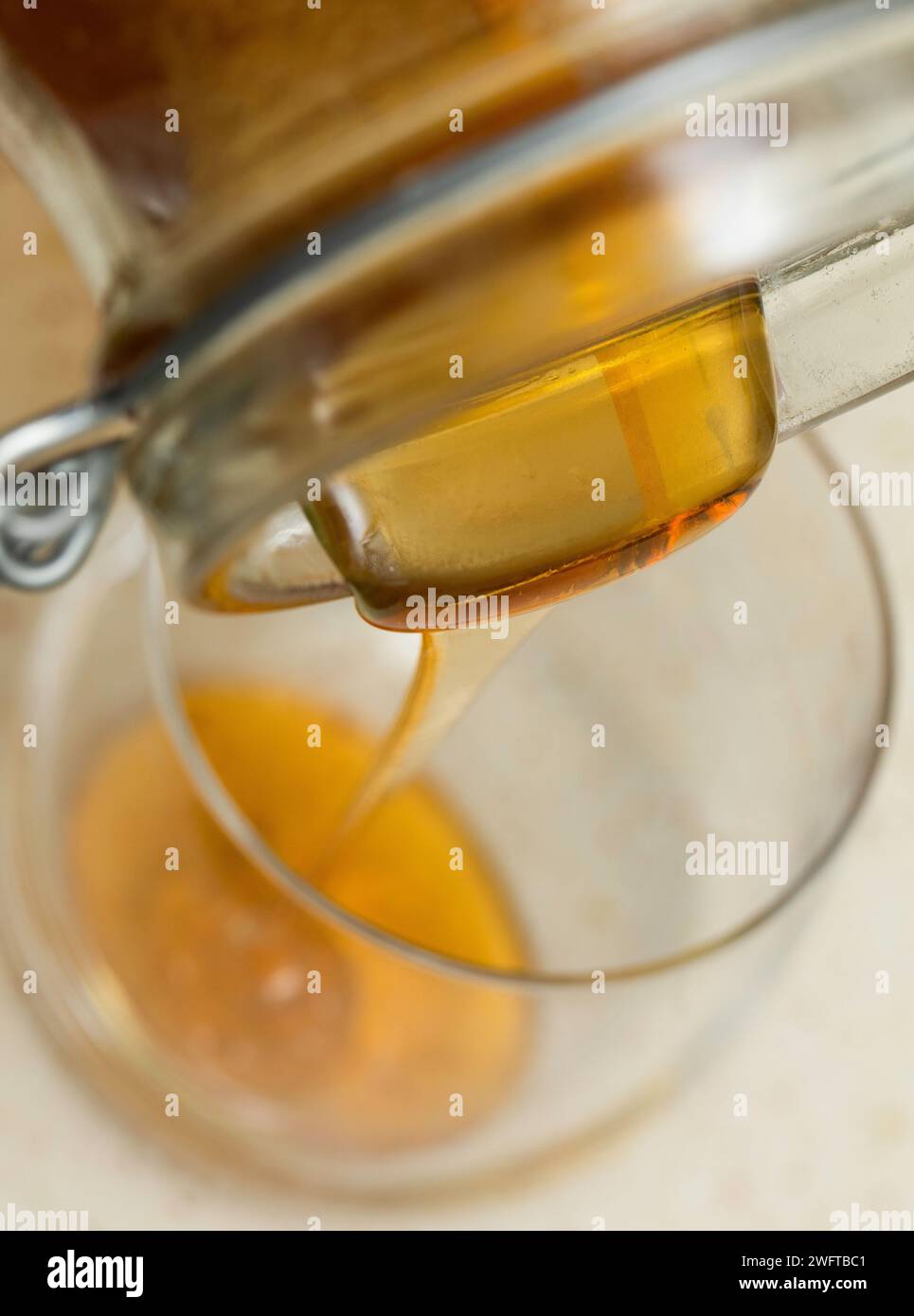 Miel liquide versé dans un verre. Une source naturelle de sucres simples et de micronutriments précieux. Banque D'Images