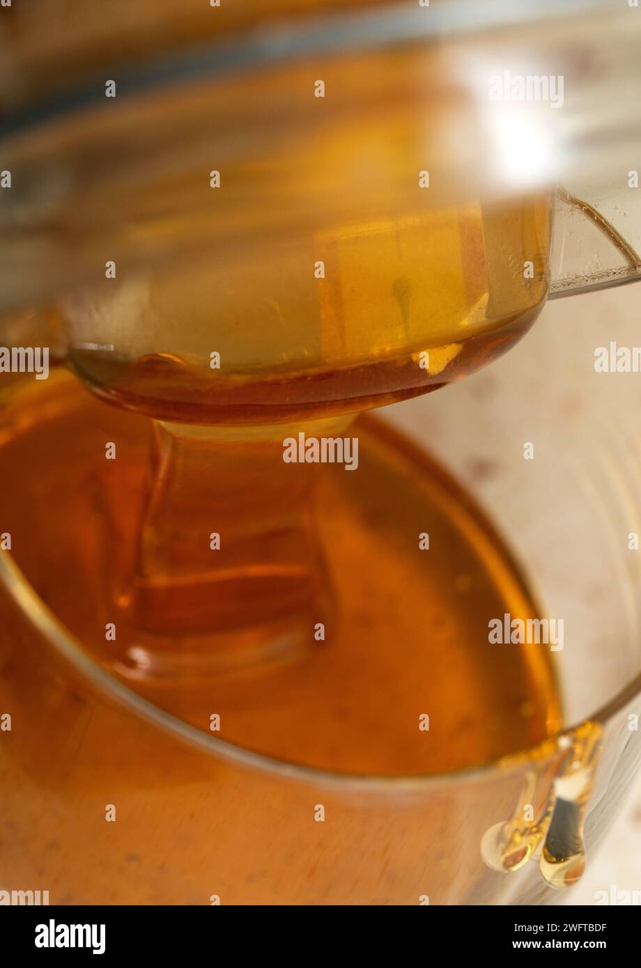 Miel liquide versé dans un verre. Une source naturelle de sucres simples et de micronutriments précieux. Banque D'Images