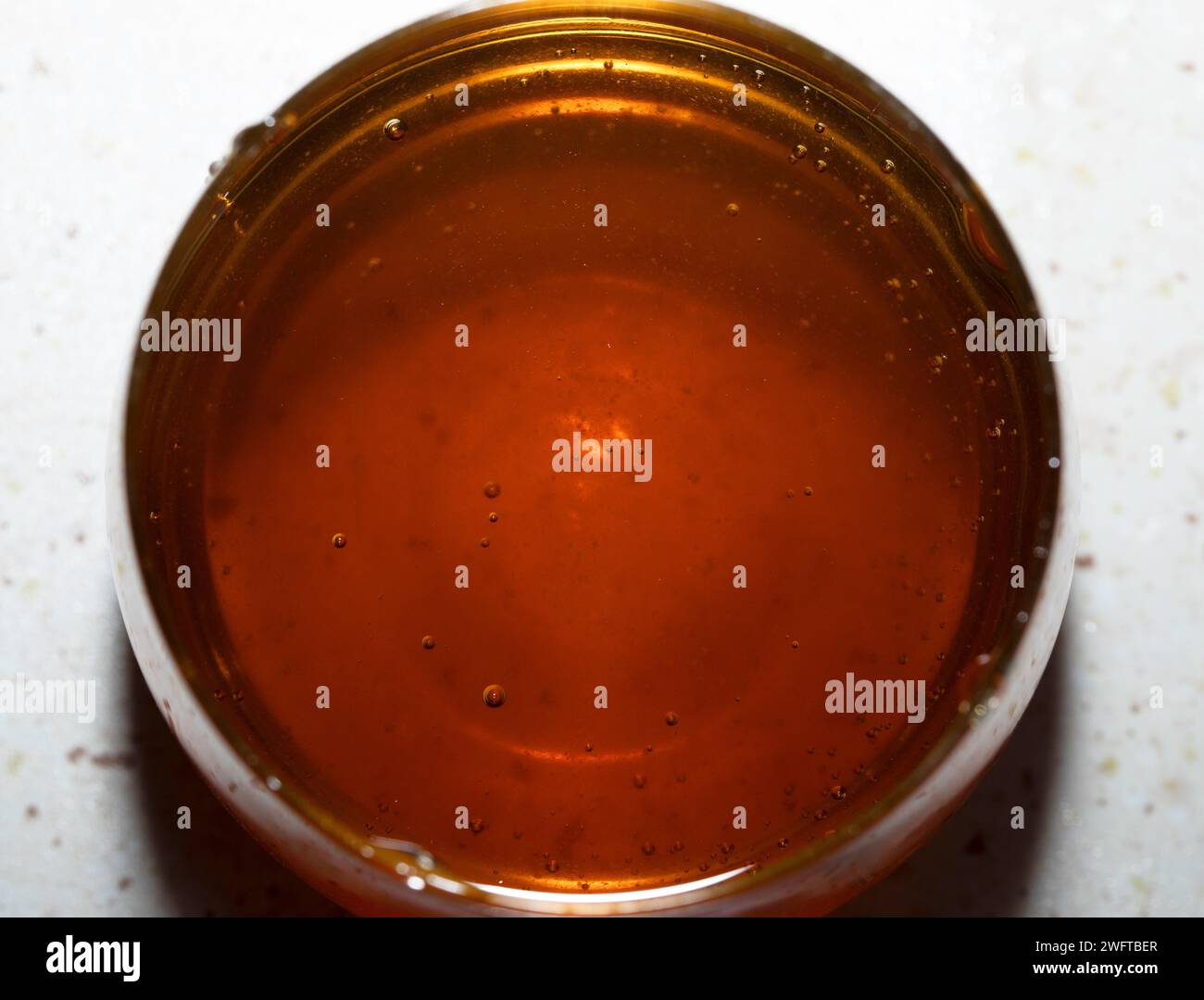 Miel liquide versé dans un verre. Une source naturelle de sucres simples et de micronutriments précieux. Banque D'Images