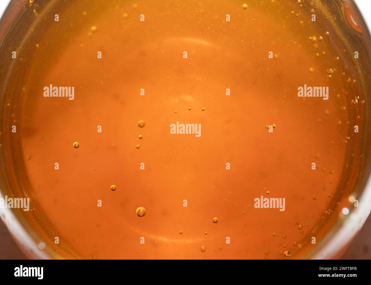 Miel liquide versé dans un verre. Une source naturelle de sucres simples et de micronutriments précieux. Banque D'Images