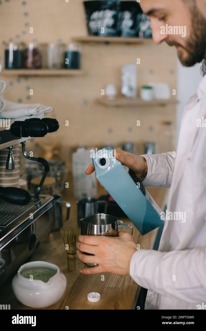 Un barista verse le lait d'une boîte en carton. Le processus de fabrication du café ou du matcha. Banque D'Images