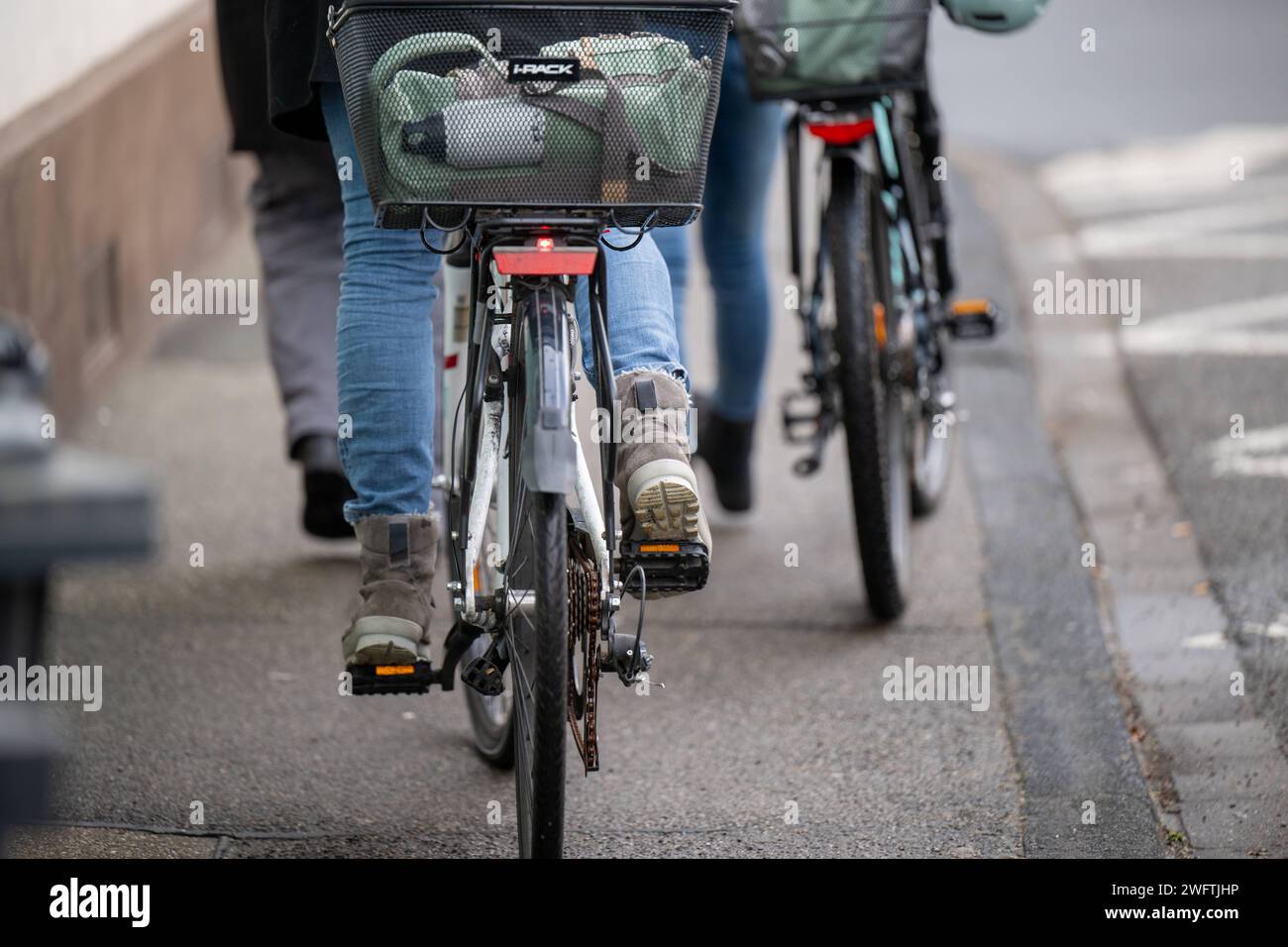 Gehwegszene mit Fahrrad und Fußgängern in Winterkleidung , Alltagssituation, Deutschland, 01.02.2024, Zwei Personen gehen auf einem Gehweg, eine davon schiebt ein Fahrrad mit einem Korb und einem Helm auf dem Gepäckträger. SIE sind von hinten fotografiert, mit einer Straßenmarkierung im hintergrund, und tragen Winterkleidung. *** Scène de trottoir avec vélo et piétons en vêtements d'hiver , situation quotidienne, Allemagne, 01 02 2024, deux personnes marchant sur un trottoir, l'un d'eux poussant un vélo avec un panier et un casque sur le transporteur ils sont photographiés de derrière, avec un marquage routier i Banque D'Images