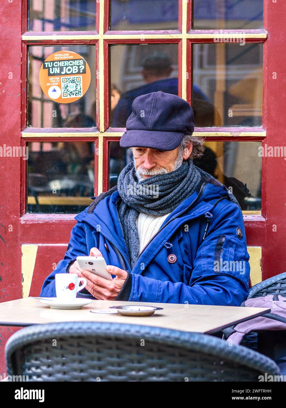 Homme plus âgé assis à la table de café en plein air vérifiant smartphone - Tours, Indre-et-Loire (37), France. Banque D'Images