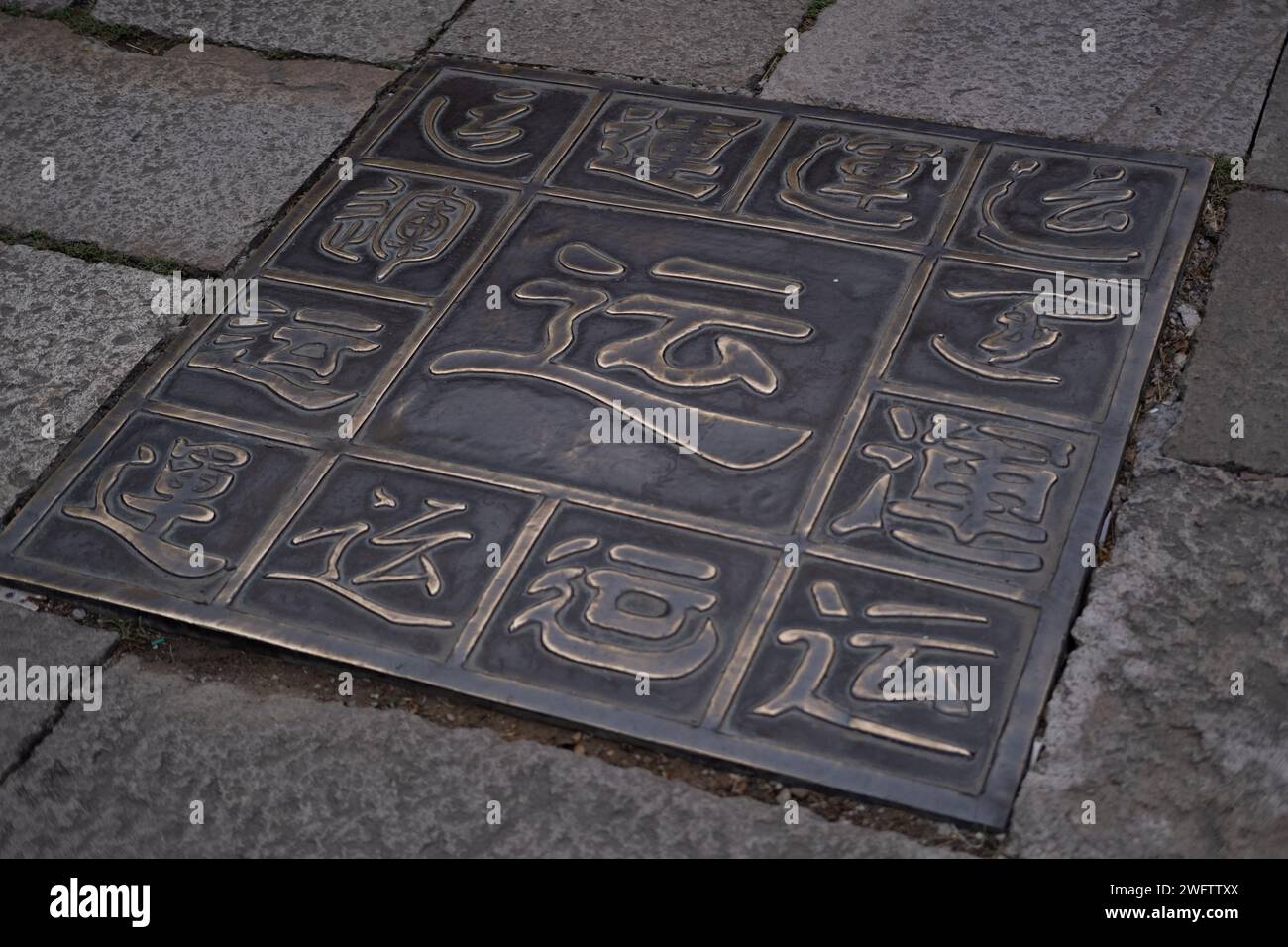Carreaux métalliques symbolisant la chance (Yun) selon la culture chinoise, placés au milieu d'une rue Banque D'Images
