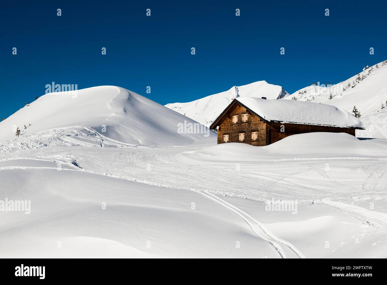 Montagnes enneigées et cabane de montagne avec piste de ski, Damuels, Bregenzerwald, Vorarlberg, Autriche Banque D'Images