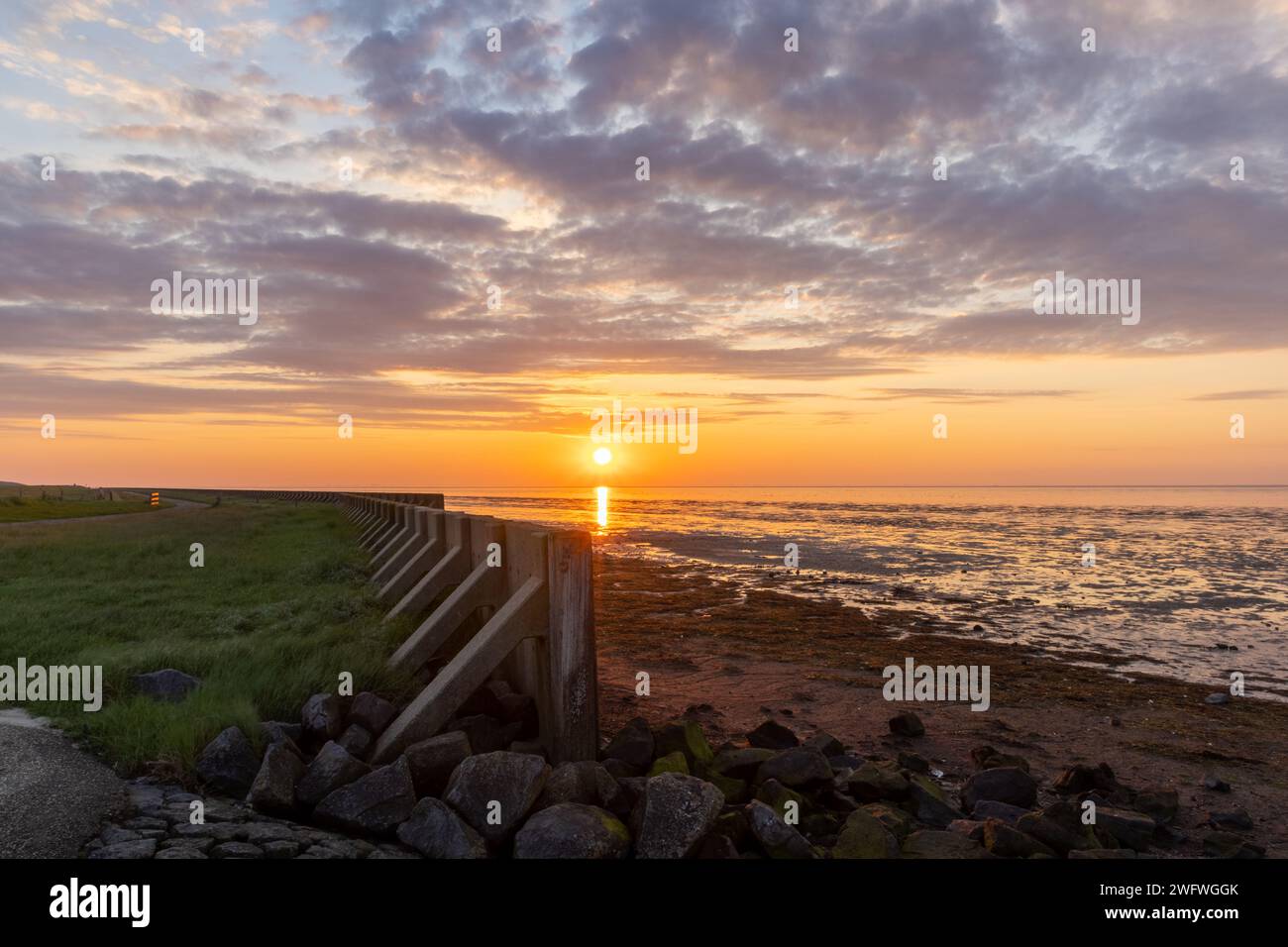 Digue en bois à la mer des Wadden (patrimoine mondial de l'UNESCO) pendant le coucher de soleil coloré Banque D'Images