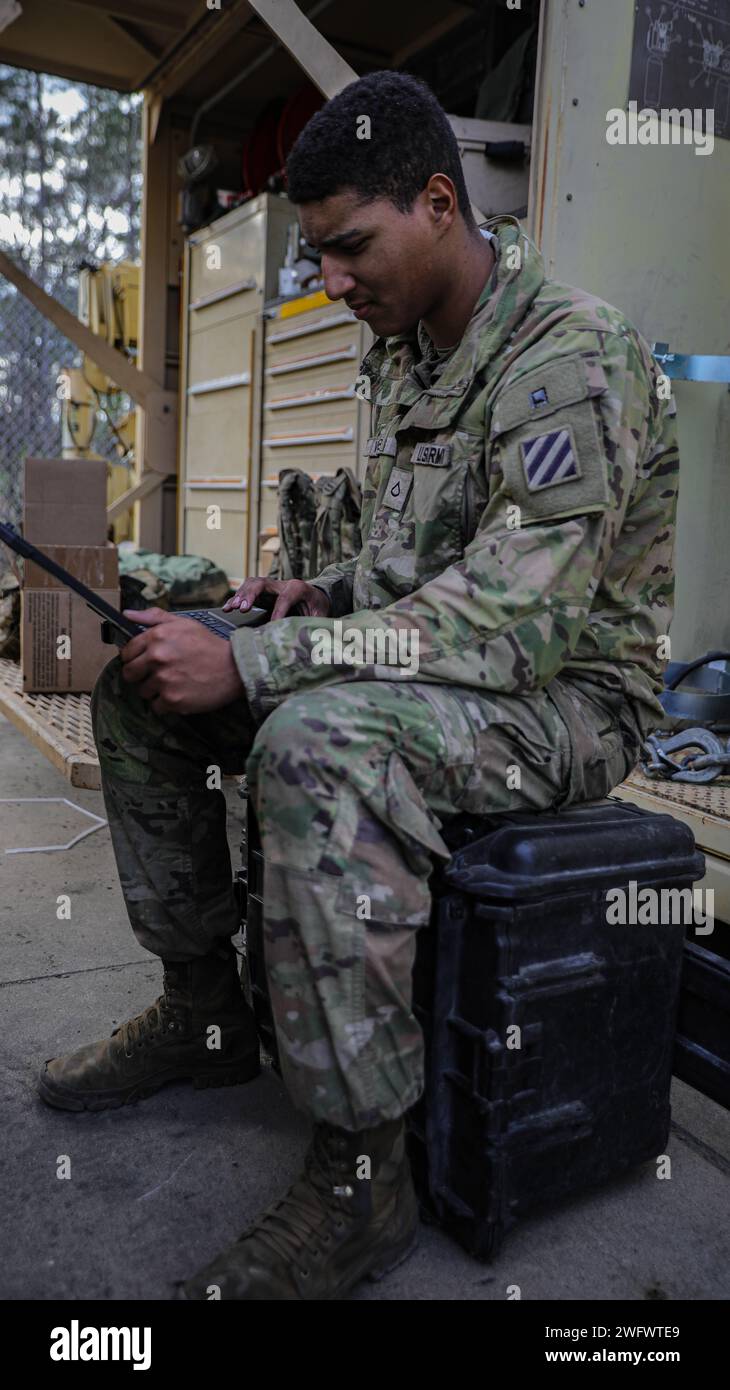 Le PFC Seth Webb, un mécanicien de char affecté au 3e bataillon, 69e régiment d'armure, 3e division d'infanterie, remplit des formulaires sur un ordinateur portable pendant la table d'artillerie V à fort Stewart, Géorgie, le 18 janvier 2024. Webb voulait à l'origine être un pétrolier ; cependant, il exploite maintenant un véhicule de récupération M88 en tant que mécanicien de réservoir. Banque D'Images