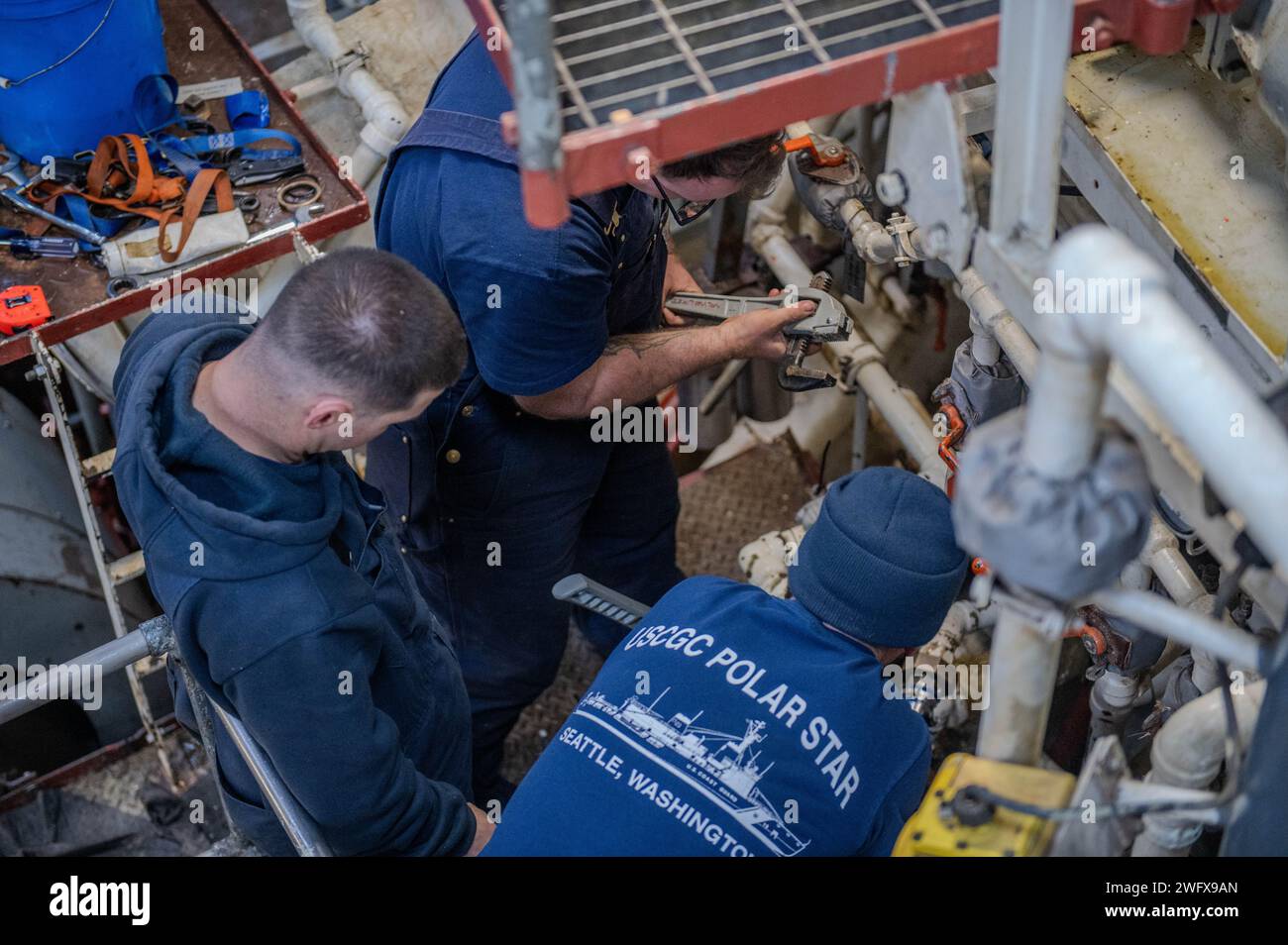 Le quartier général de la Garde côtière américaine de 1e classe Trevor Davenport, le quartier général de 1e classe Daniel Osborne et le quartier général en chef Pieter Kindberg, techniciens en machinerie, discutent de la façon de mieux sceller un tuyau sur un refroidisseur d'eau de rechange lorsqu'ils sont sur le Cutter Polar Star (WAGB 10) de la Garde côtière dans le détroit de McMurdo, en Antarctique, 12 janvier 2024. Chaque année, une équipe conjointe et totale de la force travaille ensemble pour mener à bien une saison réussie de l’opération Deep Freeze. Les membres actifs, de la Garde et de la Réserve de l'US Air Force, de l'Armée de terre, de la Garde côtière et de la Marine travaillent ensemble pour forger une JTF-SFA solide qui continue le fier métier Banque D'Images Le quartier général de la Garde côtière américaine de 1e classe Trevor Davenport, le quartier général de 1e classe Daniel Osborne et le quartier général en chef Pieter Kindberg, techniciens en machinerie, discutent de la façon de mieux sceller un tuyau sur un refroidisseur d'eau de rechange lorsqu'ils sont sur le Cutter Polar Star (WAGB 10) de la Garde côtière dans le détroit de McMurdo, en Antarctique, 12 janvier 2024. Chaque année, une équipe conjointe et totale de la force travaille ensemble pour mener à bien une saison réussie de l’opération Deep Freeze. Les membres actifs, de la Garde et de la Réserve de l'US Air Force, de l'Armée de terre, de la Garde côtière et de la Marine travaillent ensemble pour forger une JTF-SFA solide qui continue le fier métier Banque D'Images