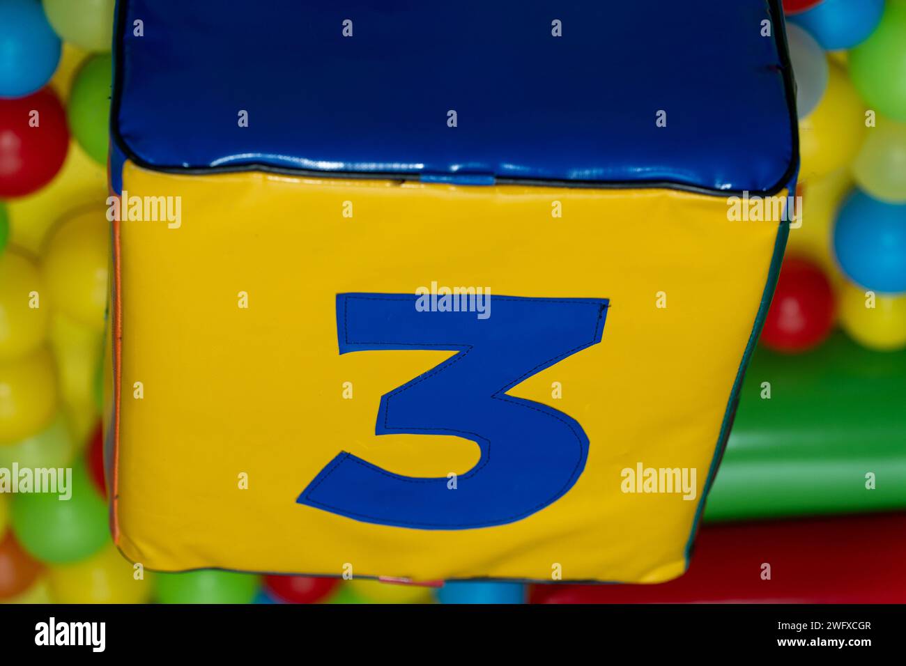 Numéro trois, couleur bleue sur fond jaune. Partie de la forme carrée de matériau en caoutchouc. Aire de jeux pour enfants. Banque D'Images