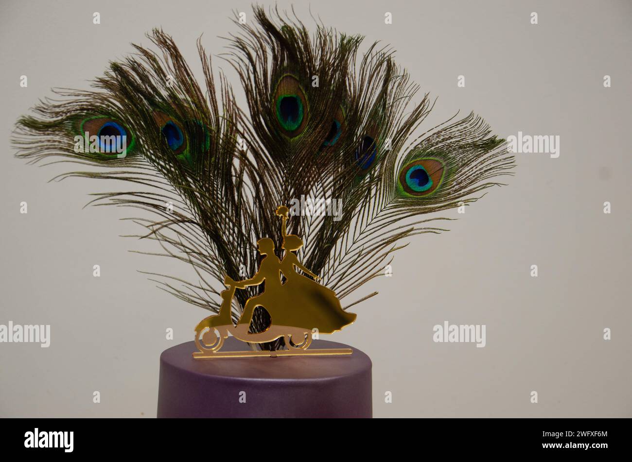 5 vraies plumes de paon vertes avec décoration dorée sur le dessus du gâteau de mariage violet Banque D'Images