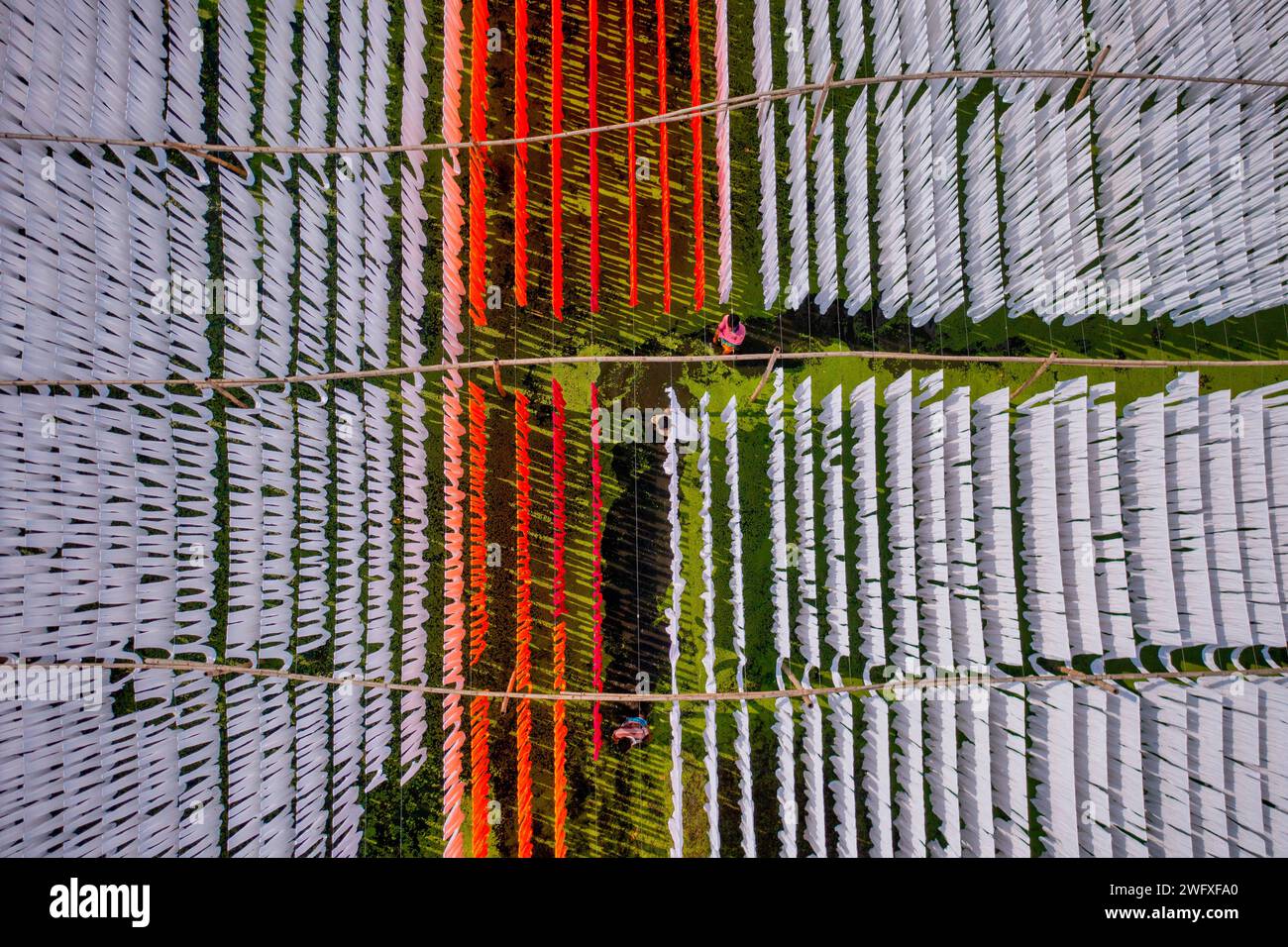 Vue aérienne de personnes travaillant dans une buanderie publique suspendue pour sécher des tissus colorés à Narayanganj, Dhaka, Bangladesh. Banque D'Images