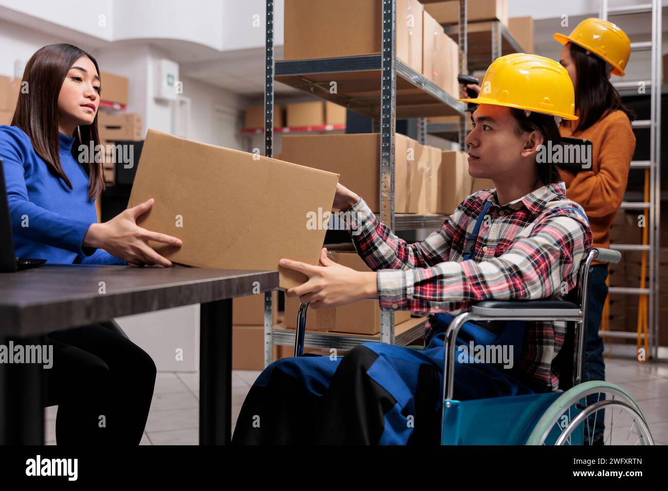 Les employés des services postaux collaborent à l'entrepôt et coordonnent la livraison. Équipe asiatique de directeur de distribution travaillant dans le magasin tout en vérifiant la qualité de l'emballage de boîte en carton Banque D'Images