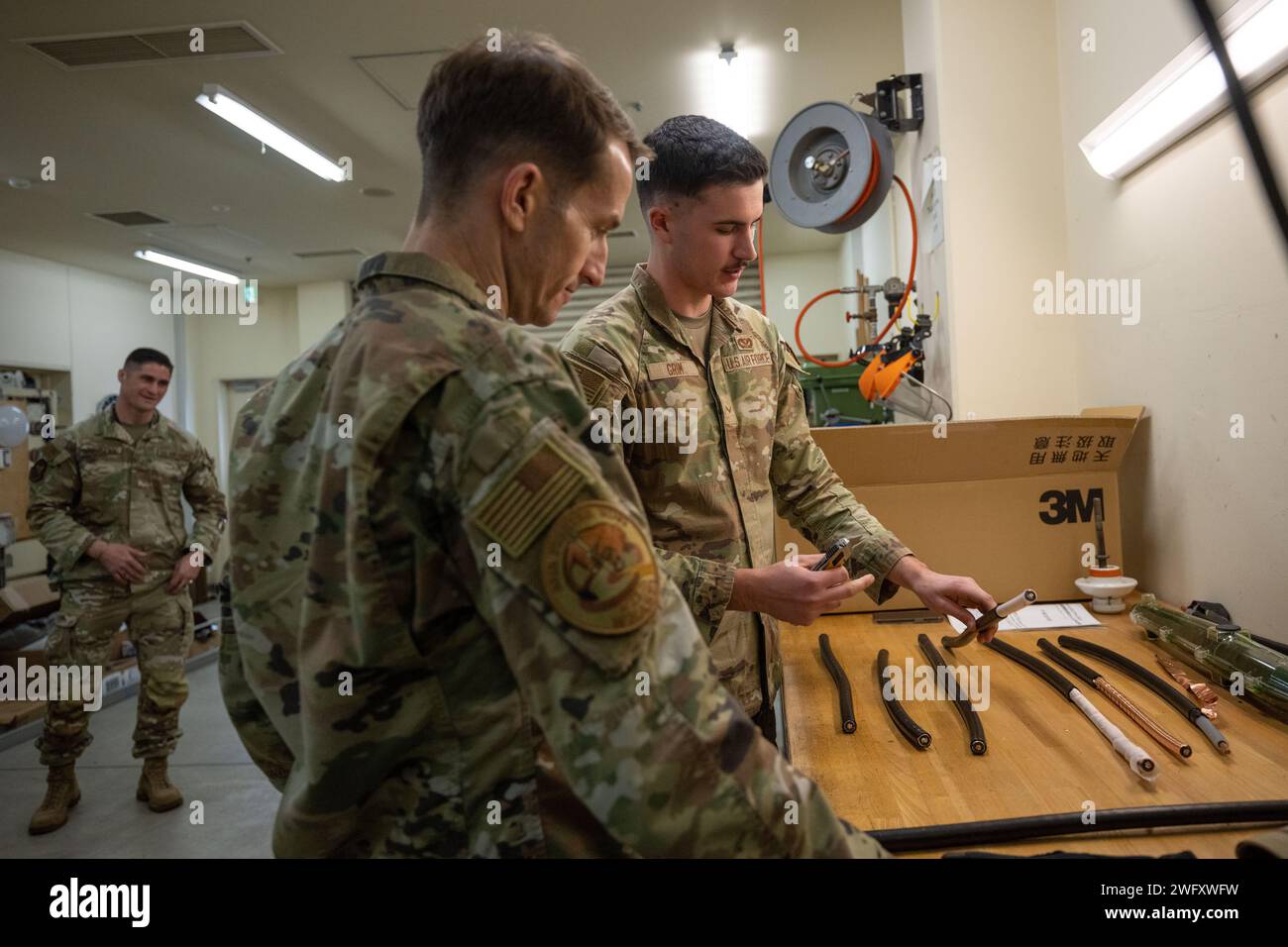 Cole Grim, apprenti en systèmes électriques du 35e escadron du génie civil, montre le processus de réparation des câbles au colonel Michael Richard, commandant du 35e Fighter Wing, lors d'une visite de Wild Weasel à la base aérienne de Misawa, Japon, le 1 4 janvier 2024. L'équipe des systèmes électriques du 35e ces surveille et maintient le fonctionnement de l'alimentation de base. Banque D'Images