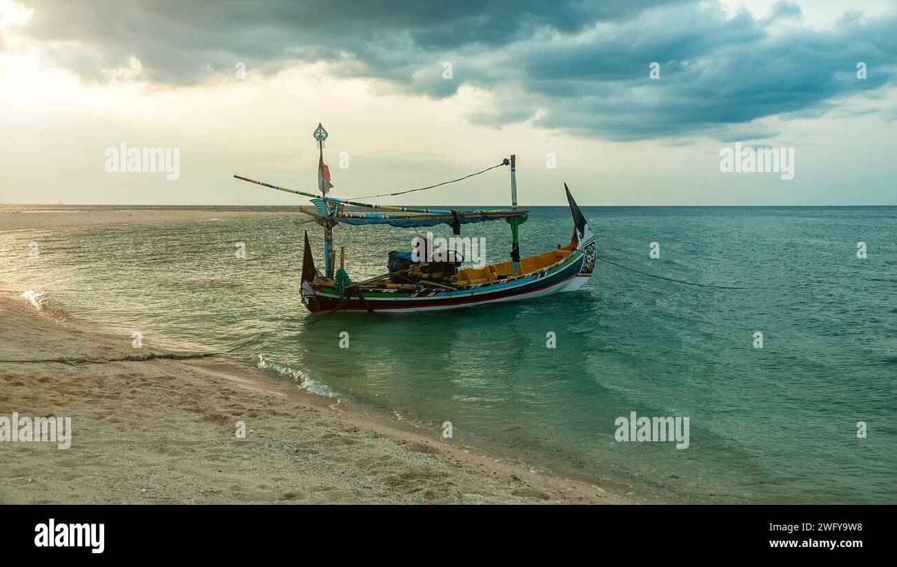 Un bateau de pêche s'arrête sur la plage avec vue sur un ciel nuageux Banque D'Images