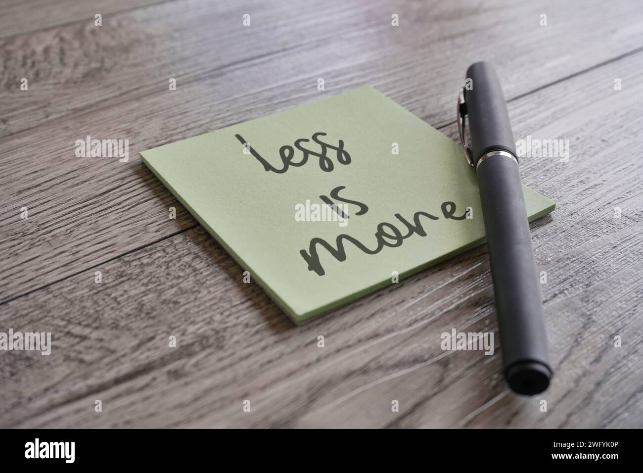 Image rapprochée de papier de note avec le texte MOINS EST PLUS et stylo. Banque D'Images