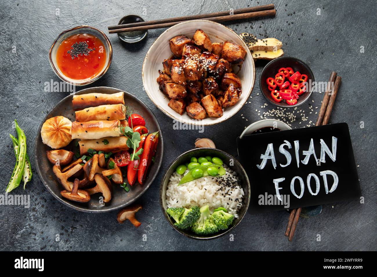 Poulet teriyaki sur fond foncé avec sauces, riz, légumes et graines de sésame. Cuisine asiatique. Vue de dessus. Banque D'Images