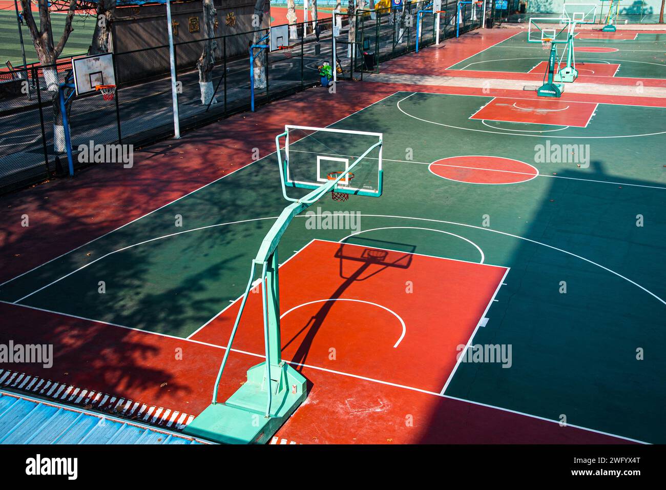 Le terrain de basket-ball universitaire ouvert, aux couleurs vives, illuminé par le chaud soleil de midi. Banque D'Images