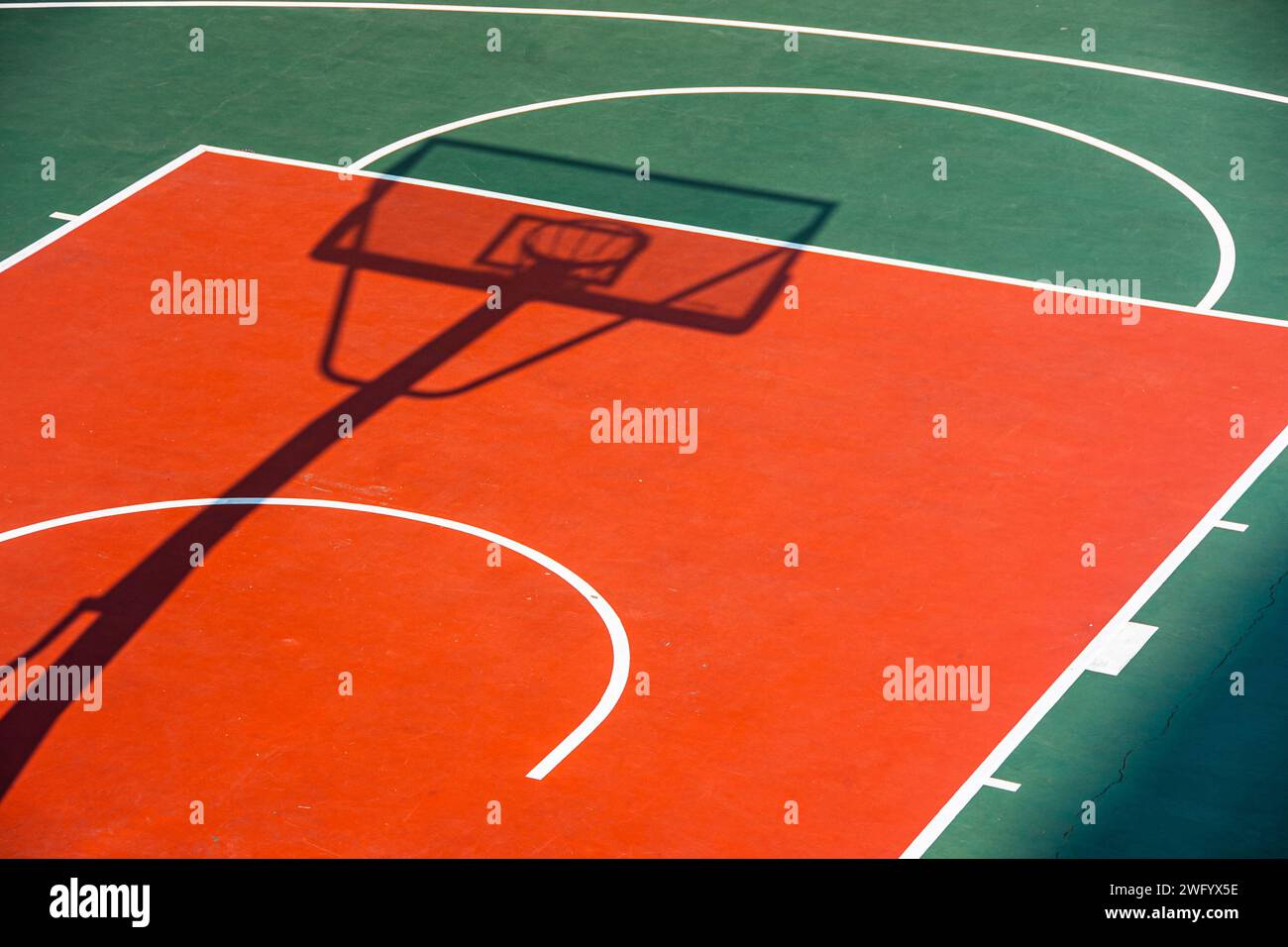Le terrain de basket-ball universitaire ouvert, aux couleurs vives, illuminé par le chaud soleil de midi. Banque D'Images