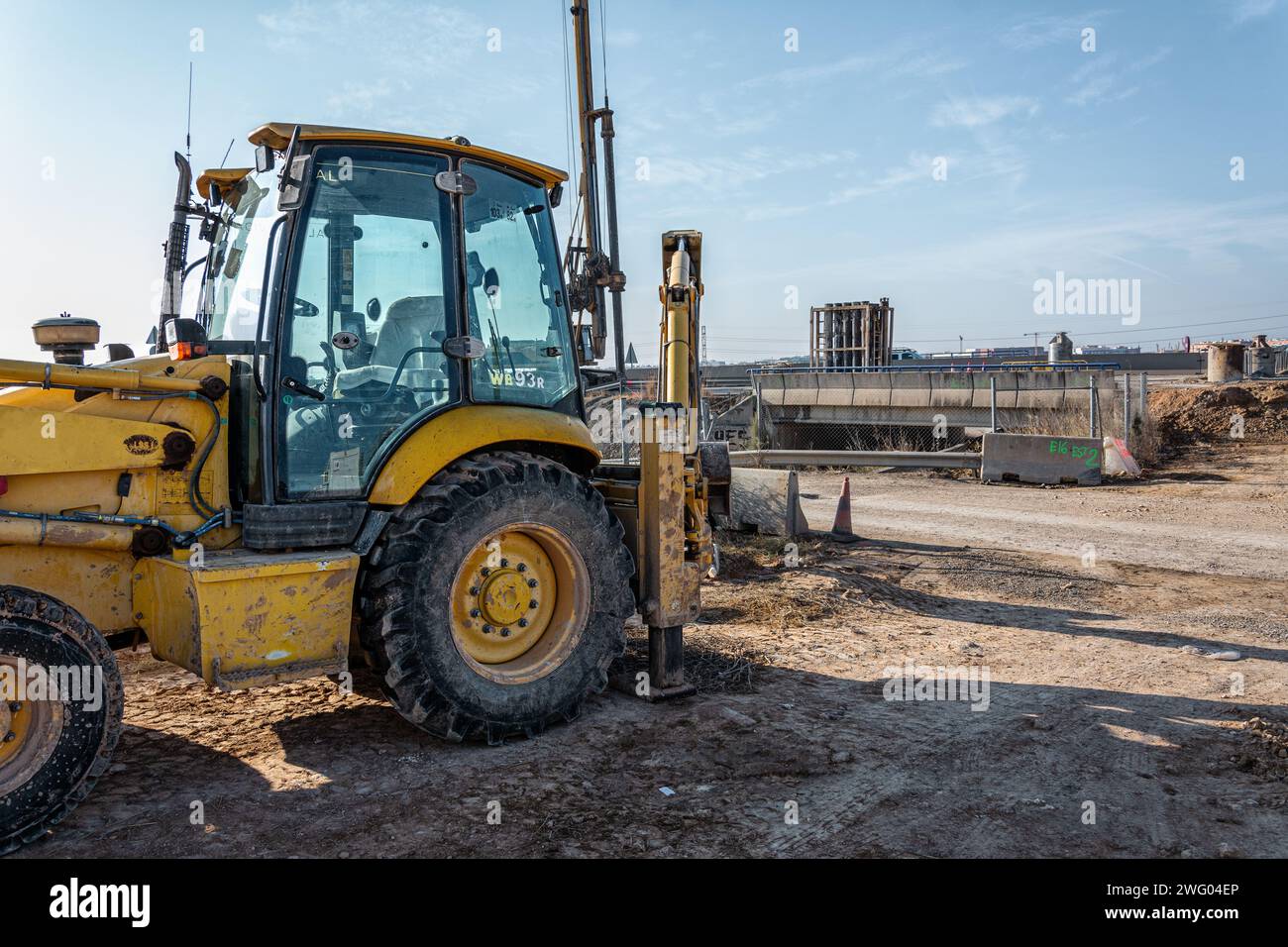 Le tracteur jaune repose sur un terrain sablonneux près d'un chantier de construction Banque D'Images