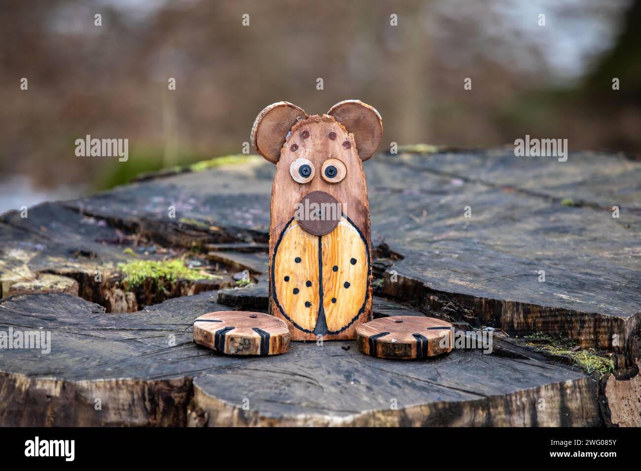 Chien jouet en bois sur une souche dans la forêt, gros plan avec flou. Banque D'Images