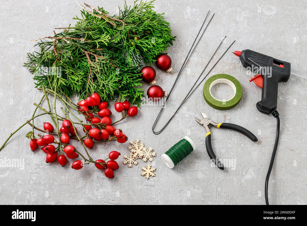 Un fleuriste au travail : Comment faire de noël traditionnelle couronne de porte avec thuja brindilles et Wild Rose fruits. Pas à pas, tutoriel. Banque D'Images