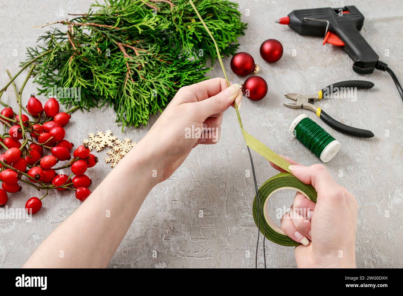 Un fleuriste au travail : Comment faire de noël traditionnelle couronne de porte avec thuja brindilles et Wild Rose fruits. Pas à pas, tutoriel. Banque D'Images