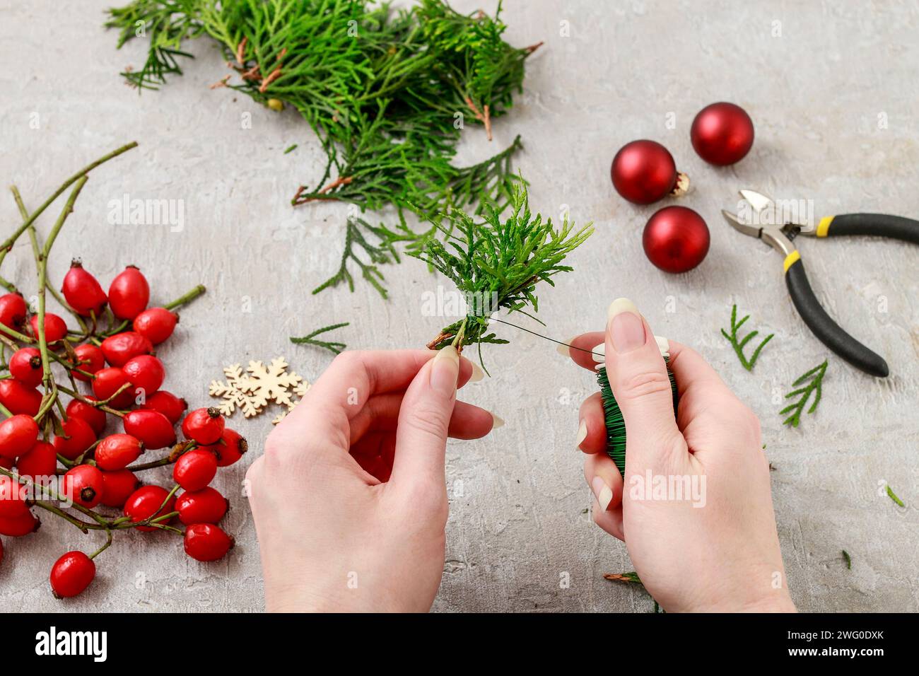 Un fleuriste au travail : Comment faire de noël traditionnelle couronne de porte avec thuja brindilles et Wild Rose fruits. Pas à pas, tutoriel. Banque D'Images