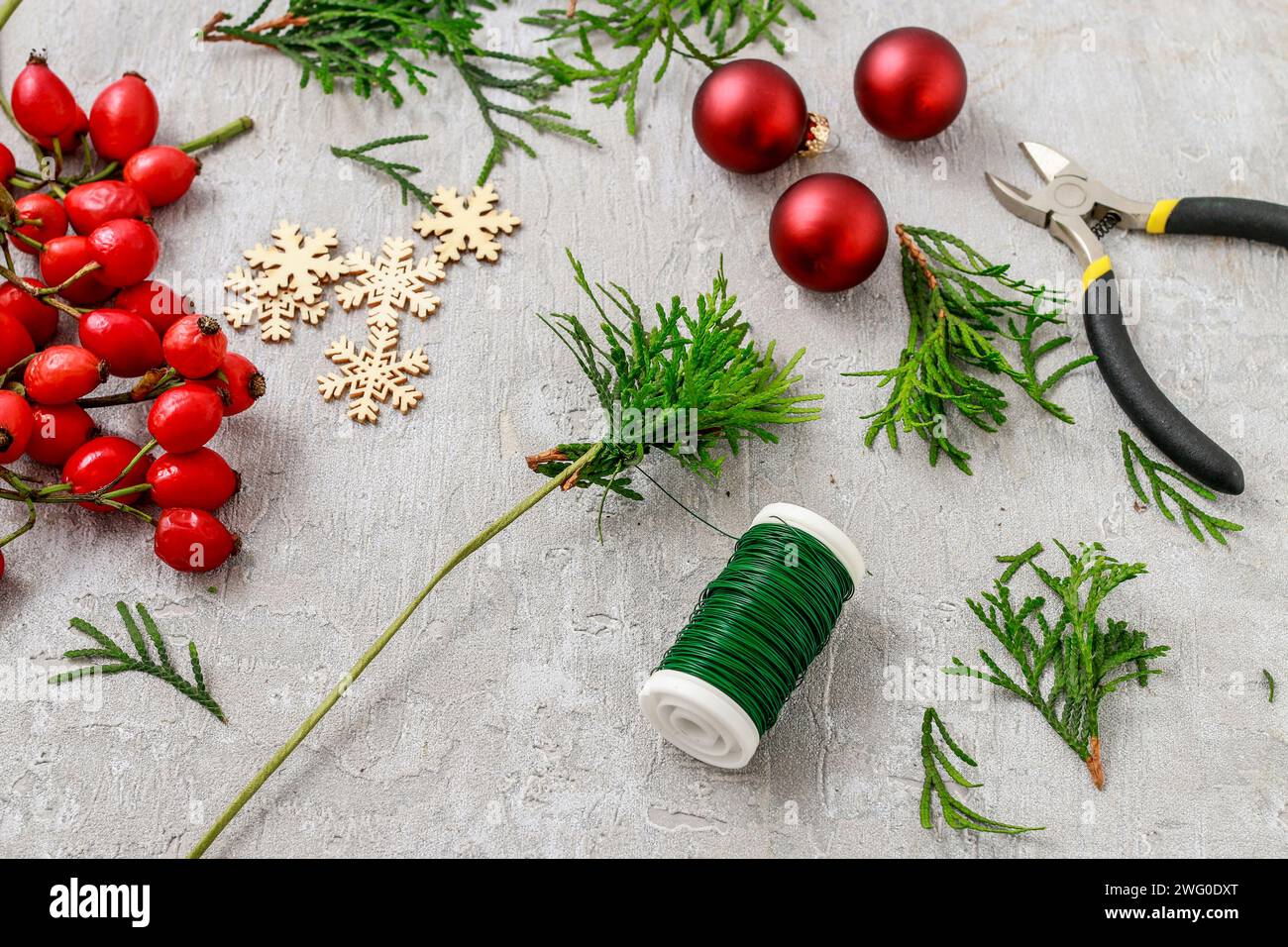 Un fleuriste au travail : Comment faire de noël traditionnelle couronne de porte avec thuja brindilles et Wild Rose fruits. Pas à pas, tutoriel. Banque D'Images