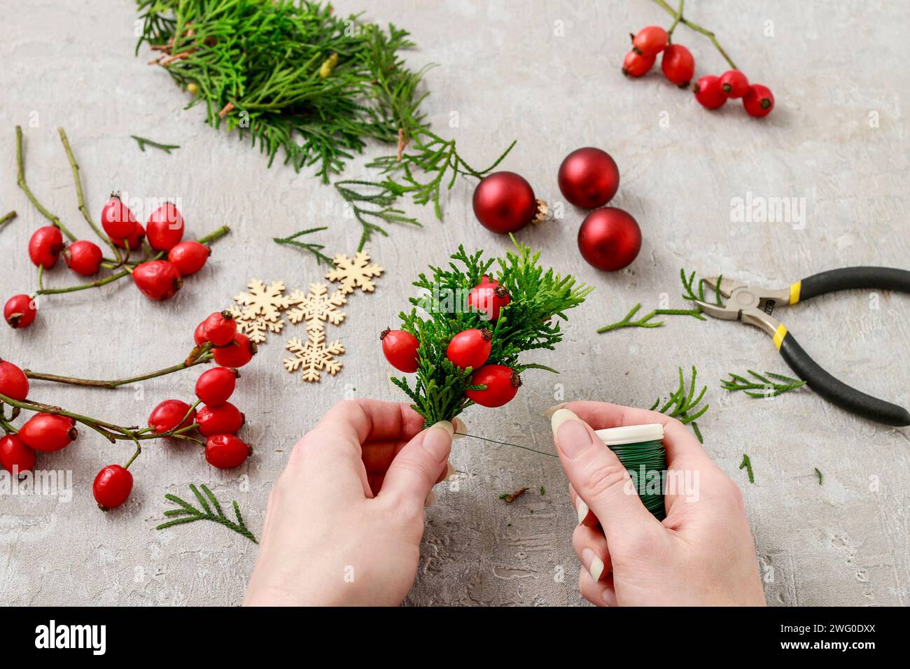 Un fleuriste au travail : Comment faire de noël traditionnelle couronne de porte avec thuja brindilles et Wild Rose fruits. Pas à pas, tutoriel. Banque D'Images
