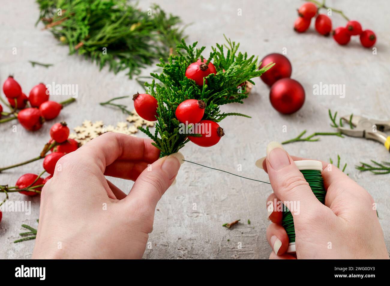 Un fleuriste au travail : Comment faire de noël traditionnelle couronne de porte avec thuja brindilles et Wild Rose fruits. Pas à pas, tutoriel. Banque D'Images