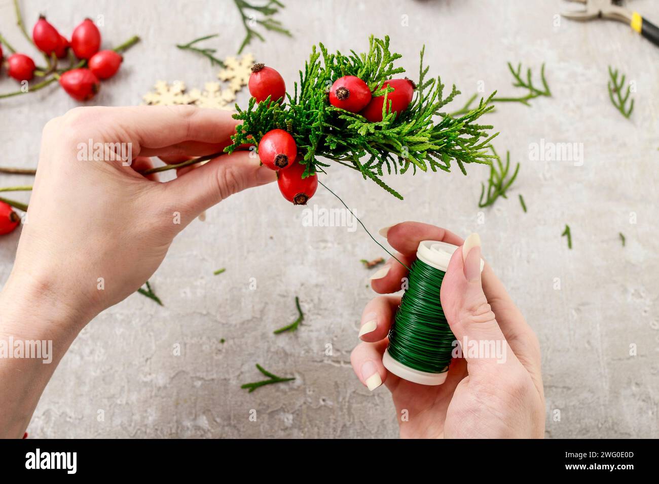 Un fleuriste au travail : Comment faire de noël traditionnelle couronne de porte avec thuja brindilles et Wild Rose fruits. Pas à pas, tutoriel. Banque D'Images