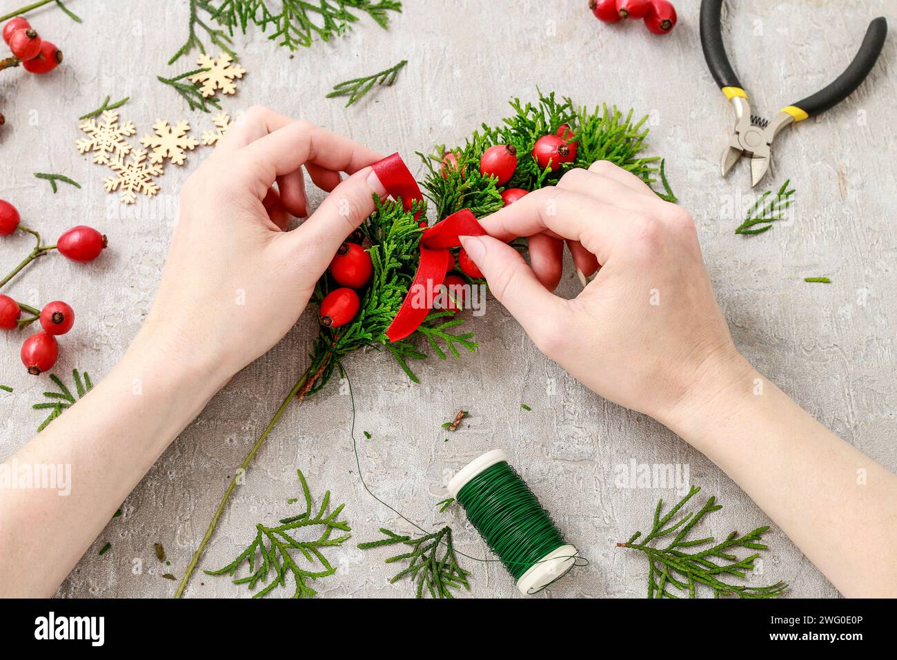 Un fleuriste au travail : Comment faire de noël traditionnelle couronne de porte avec thuja brindilles et Wild Rose fruits. Pas à pas, tutoriel. Banque D'Images