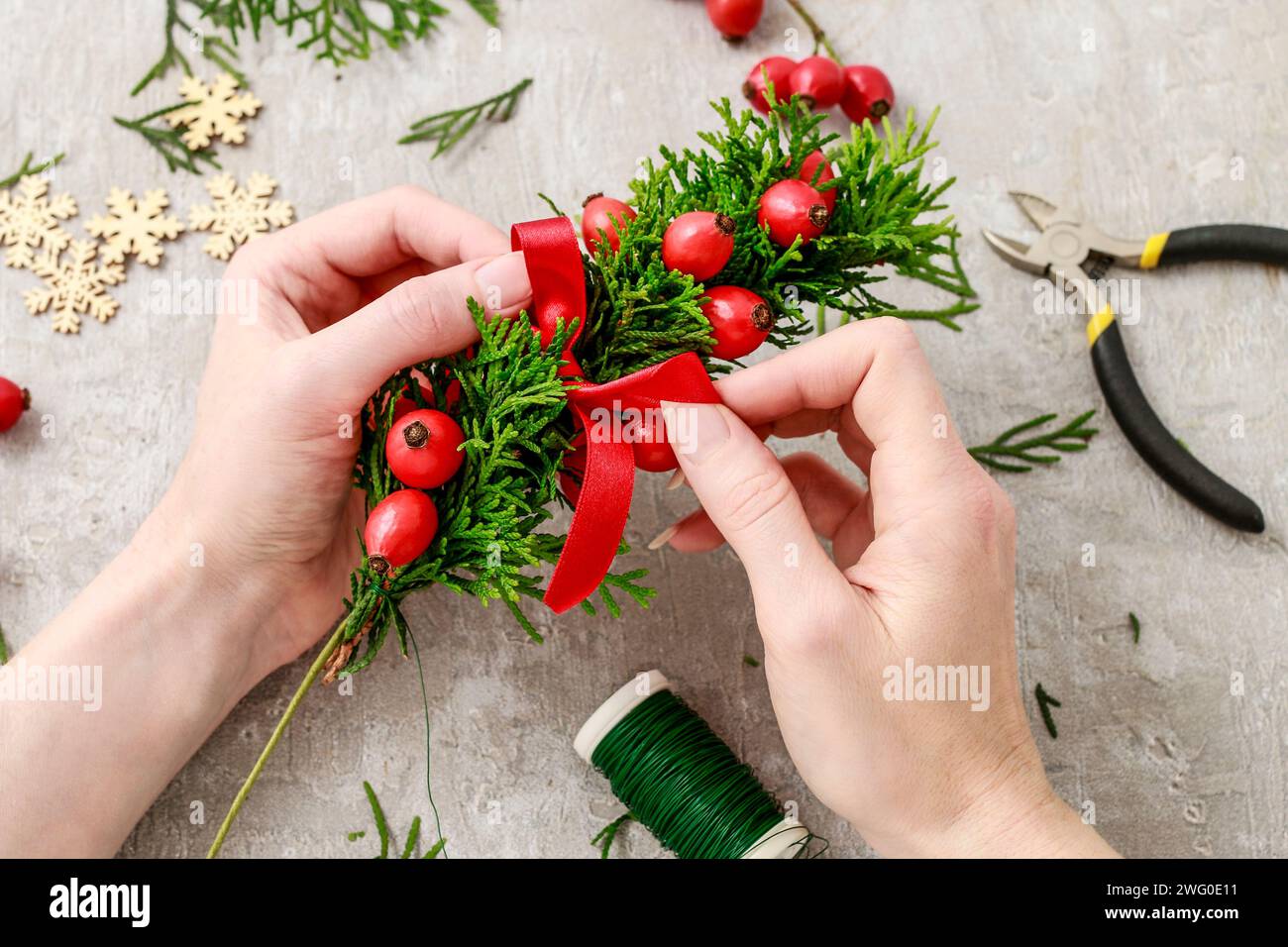 Un fleuriste au travail : Comment faire de noël traditionnelle couronne de porte avec thuja brindilles et Wild Rose fruits. Pas à pas, tutoriel. Banque D'Images