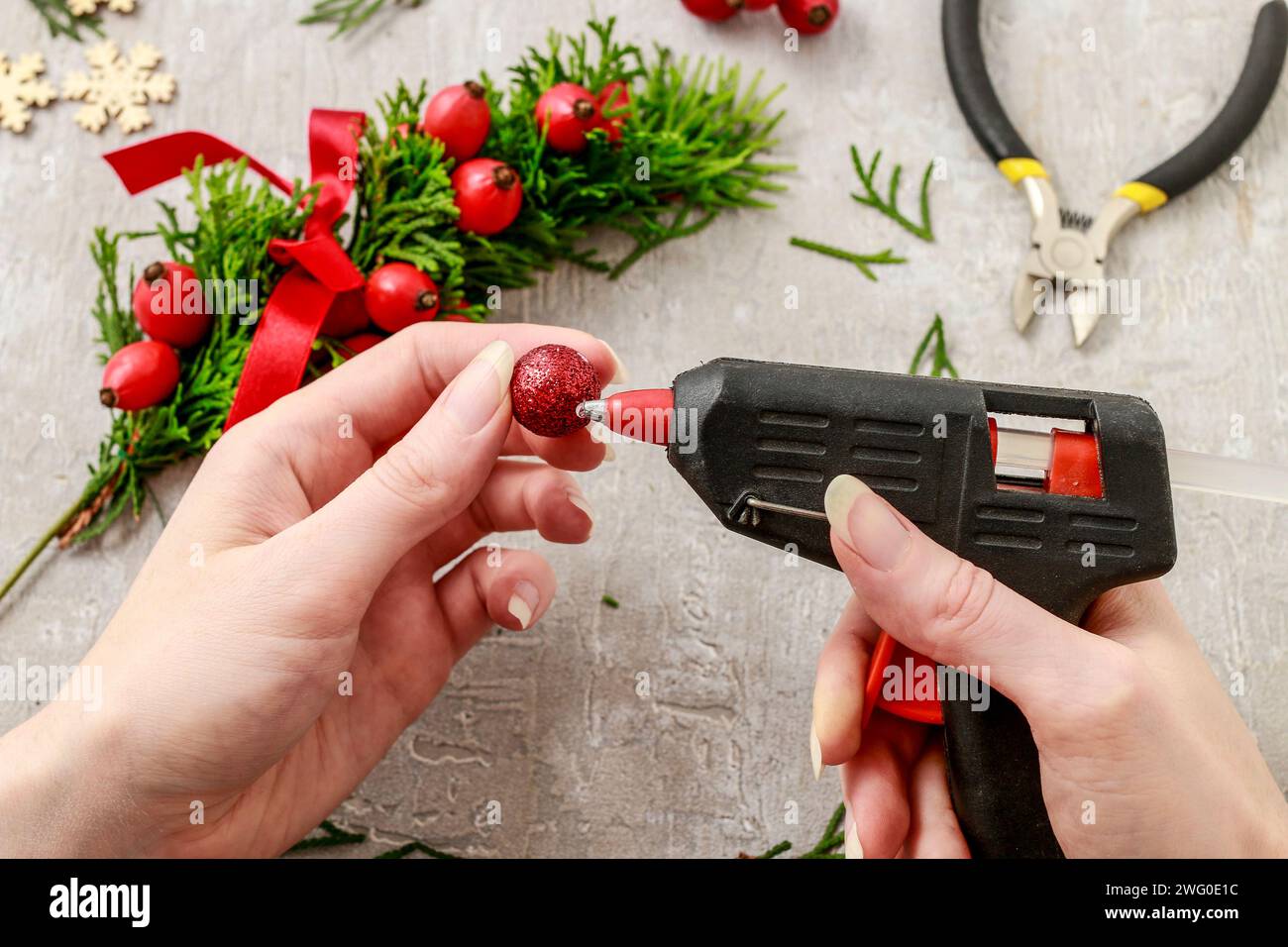 Un fleuriste au travail : Comment faire de noël traditionnelle couronne de porte avec thuja brindilles et Wild Rose fruits. Pas à pas, tutoriel. Banque D'Images