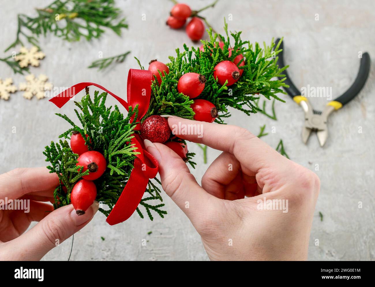 Un fleuriste au travail : Comment faire de noël traditionnelle couronne de porte avec thuja brindilles et Wild Rose fruits. Pas à pas, tutoriel. Banque D'Images