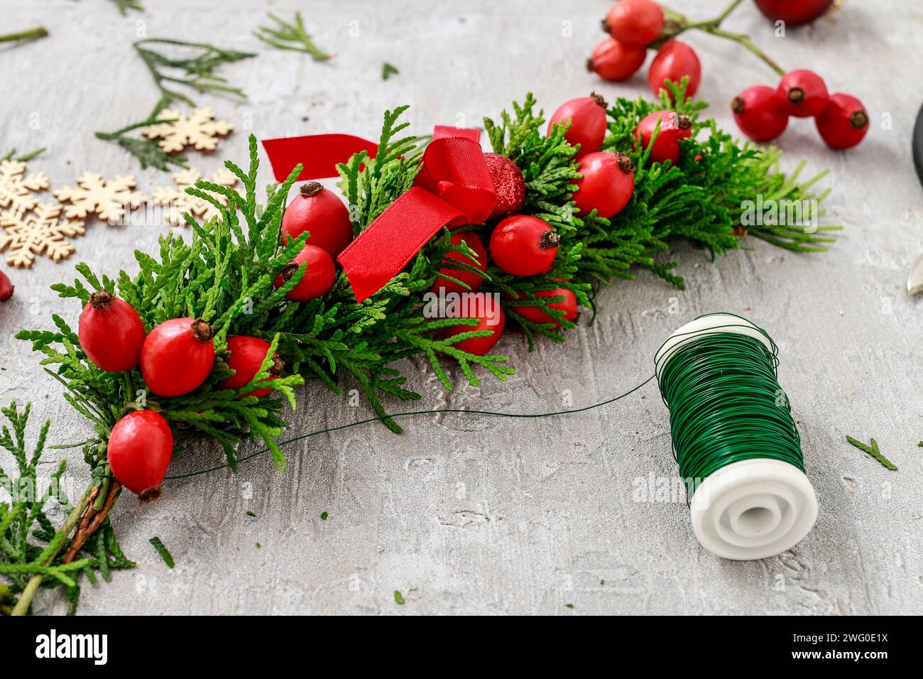 Un fleuriste au travail : Comment faire de noël traditionnelle couronne de porte avec thuja brindilles et Wild Rose fruits. Pas à pas, tutoriel. Banque D'Images