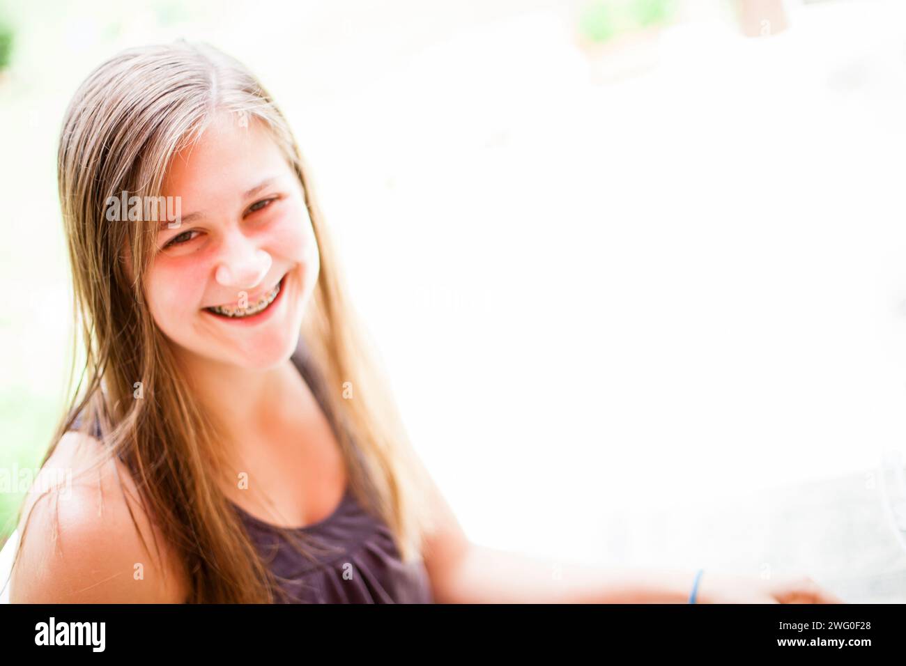 Une fille de 16 ans sourit en étant assise dehors. Banque D'Images