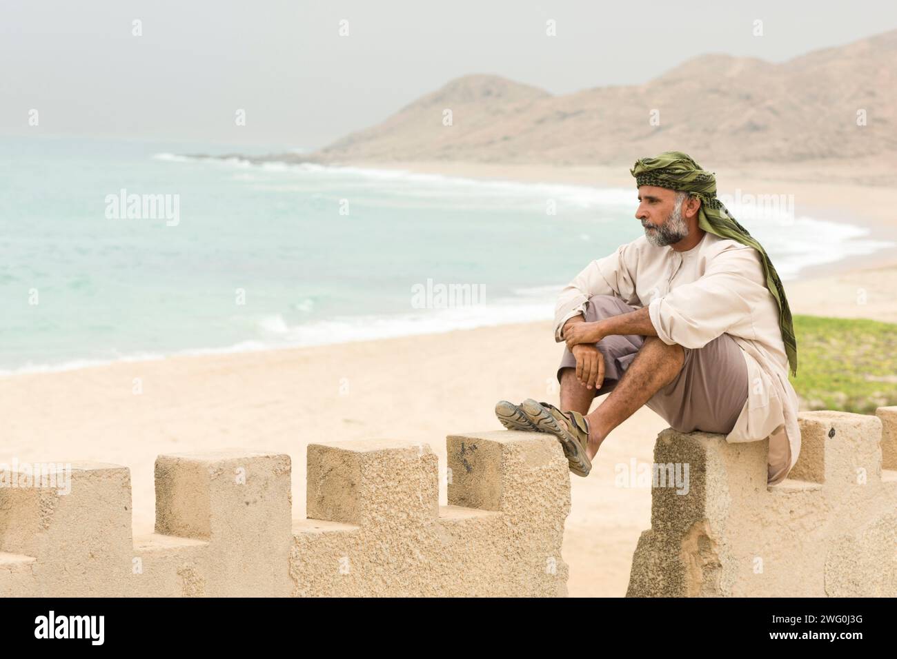 Un homme omanais repose à Mirbat, Oman avec la mer en arrière-plan. Banque D'Images