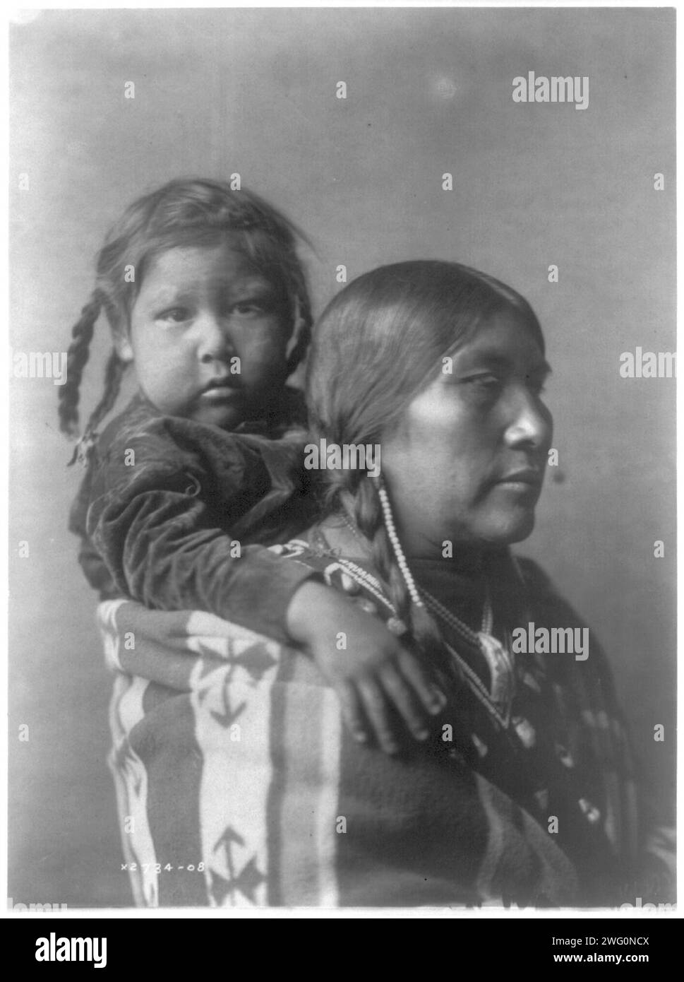 Mère Apsaroke, c1908. Femme Arapsoke, portrait tête et épaules, face à droite, enfant attaché sur son dos avec une couverture. Banque D'Images