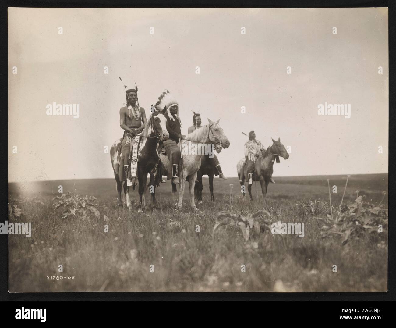 Le parti de guerre, 1905. La photographie montre un groupe d'Indiens Crow à cheval. Chef, au milieu, coiffé. Banque D'Images Le parti de guerre, 1905. La photographie montre un groupe d'Indiens Crow à cheval. Chef, au milieu, coiffé. Banque D'Images