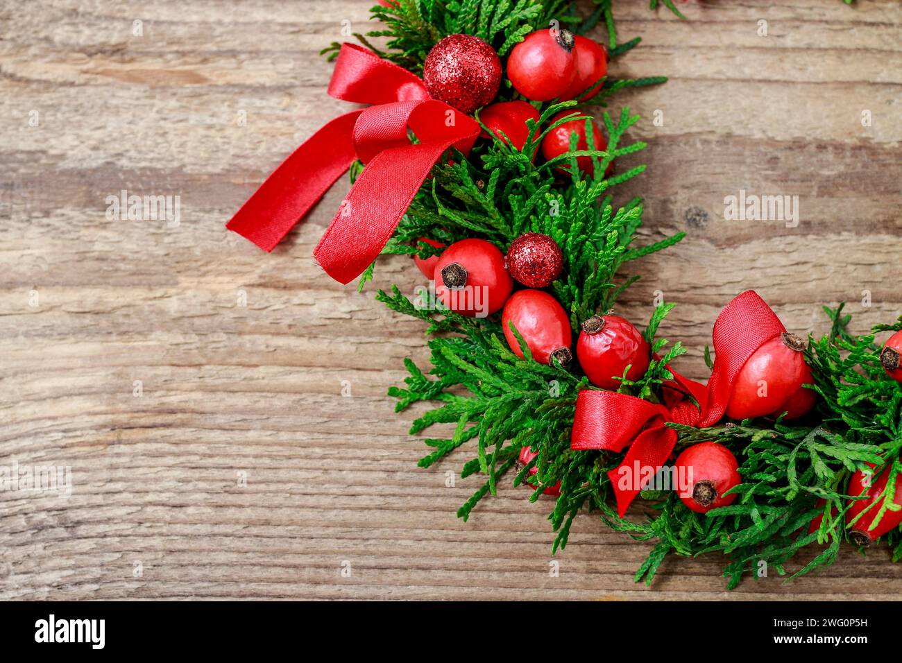 Couronne de porte de Noël traditionnel avec des brindilles et thuja vert rose fruits sauvages. Décoration de fête Banque D'Images